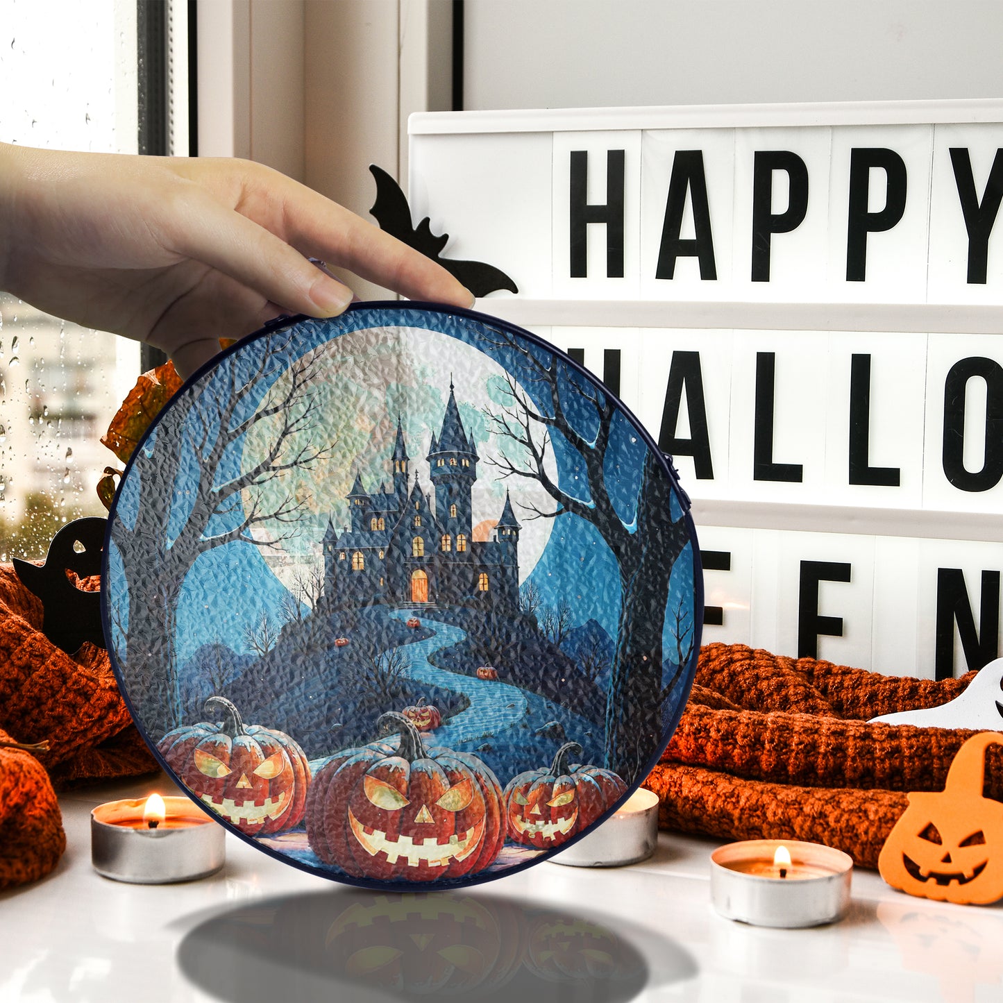 Round Halloween stained-glass style suncatcher with haunted castle and jack-o’-lantern pumpkins, hanging by a chain.