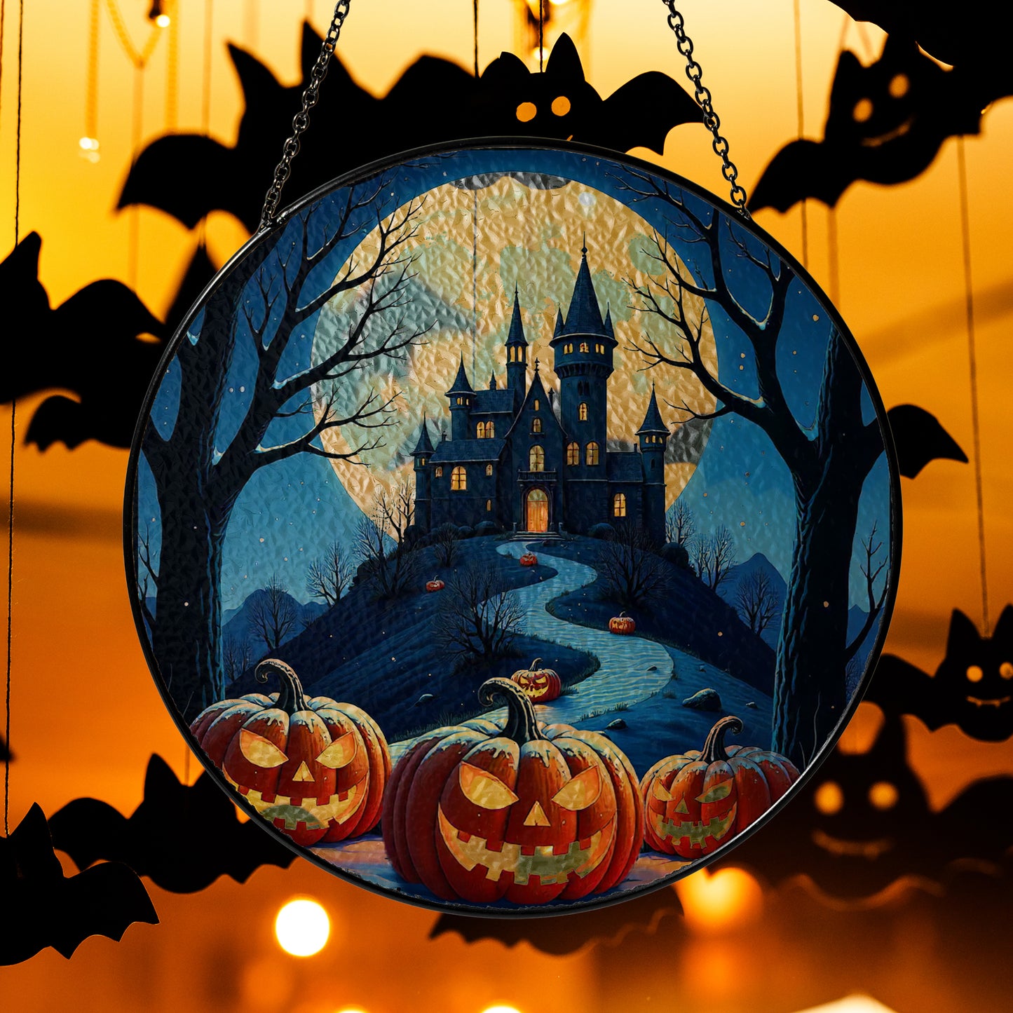 Round Halloween stained-glass style suncatcher with haunted castle and jack-o’-lantern pumpkins, hanging by a chain.