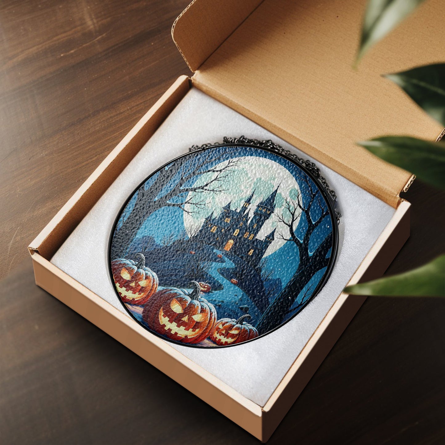 Round Halloween stained-glass style suncatcher with haunted castle and jack-o’-lantern pumpkins, hanging by a chain.